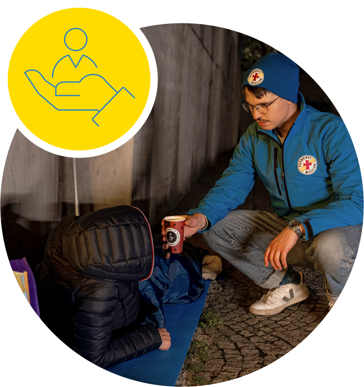 Obdachloser Mensch bekommt einen warmen Tee von einem Mitarbeiter der Bahnhofsmission Würzburg