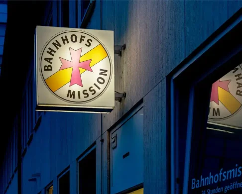 Bahnhofsmission Schild beleuchtet bei Nacht